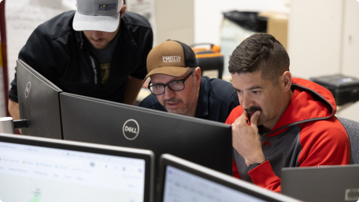 Power lines in the middle of a field with trees and blue sky