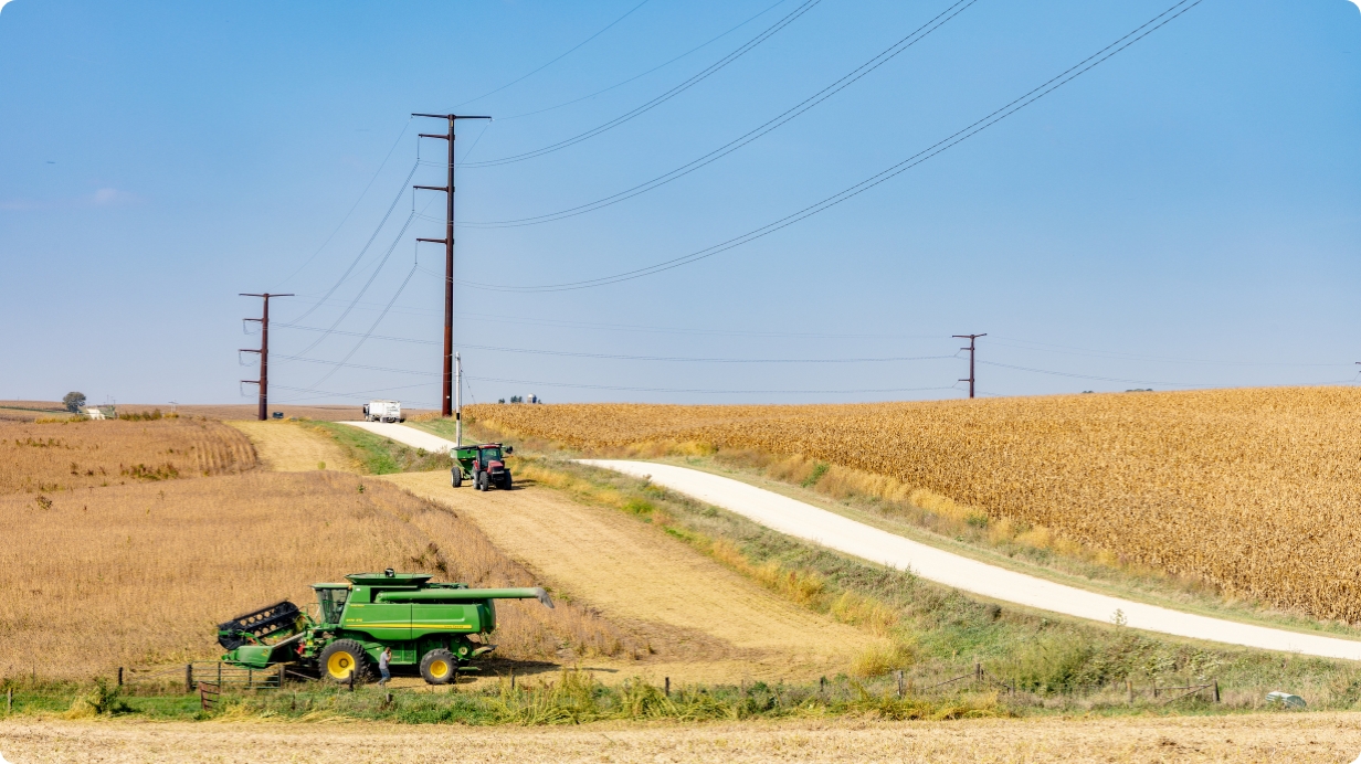 Man in safety gear spotting a lineman in a truck bucket repairing a power line